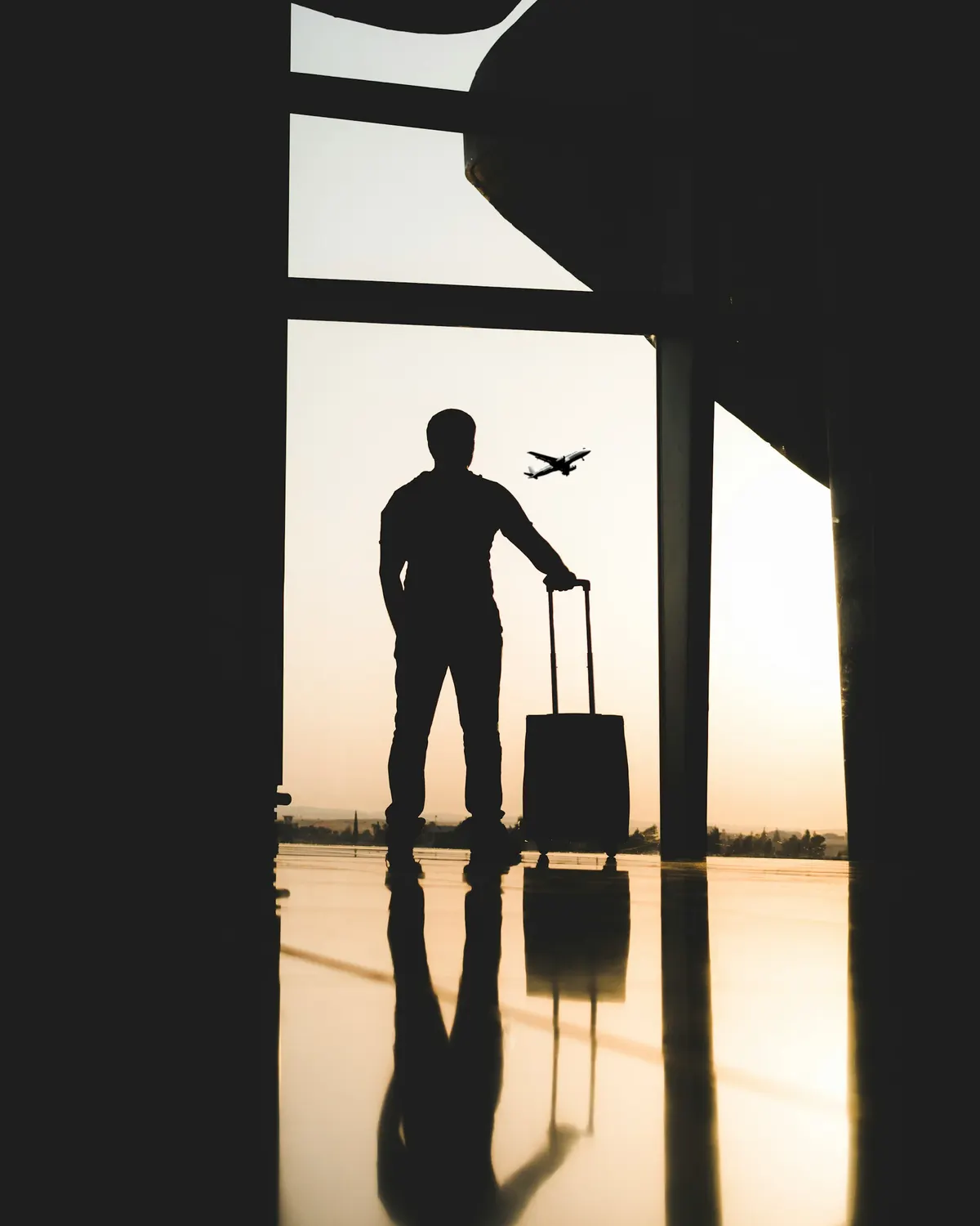 Viajante com mala observando um avião decolar no aeroporto
